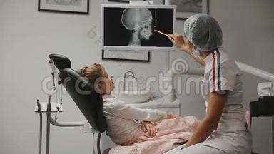 办公室牙医正畸牙医显示x光图像的牙齿，并持有建议和支架。